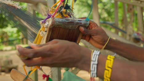 de las manos de una persona africana tejiendo tejido de seda kente en cámara lenta