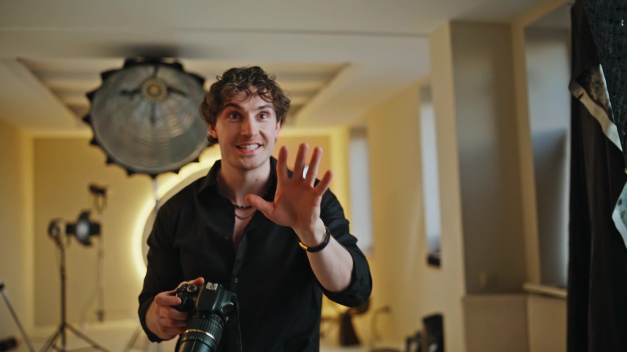 Fotografo che punta la macchina fotografica in studio. Fotografo riccio che scatta foto in interni