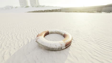 lifebuoy rests on sandy beach at sunrise near coastal buildings
