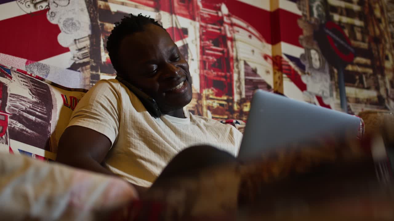 Man relaxing at home, using phone and laptop, cozy atmosphere