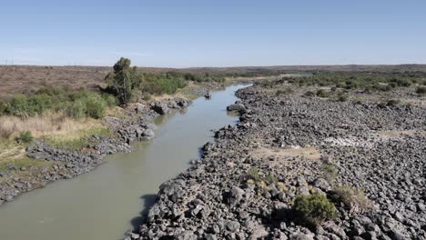 rocky shoreline of muddy orange river in karoo south africa dry season