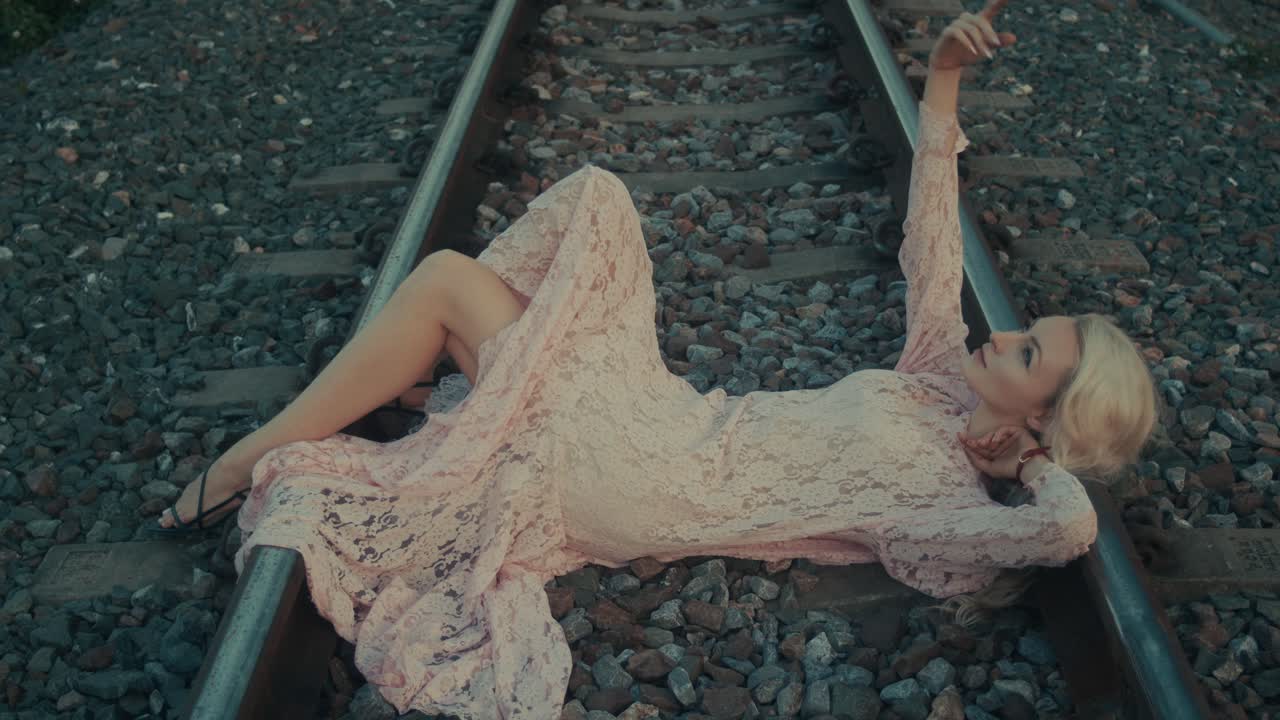 Woman in a Pink Lace Dress on Train Tracks