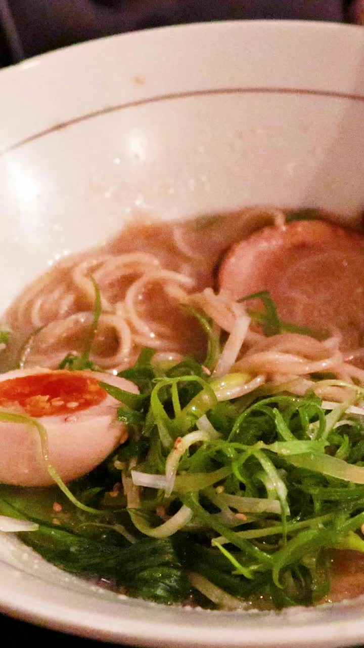 가락이 라멘 그에서 누들을 들어 올리고 있다