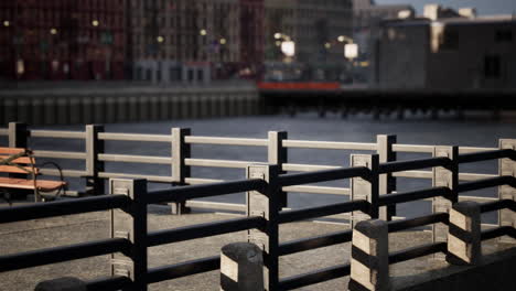 a city scene with a bench on a dock near a river