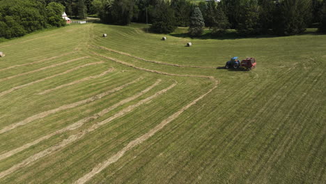 Aerial-View-Of-Tractor-Producing-Round-Bales-Of-Hay-In-Oronoco,-Minnesota,-USA---drone-shot