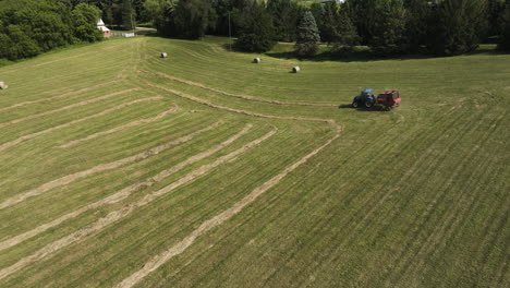 aerial view of tractor producing round bales of hay in oronoco, minnesota, usa - drone shot