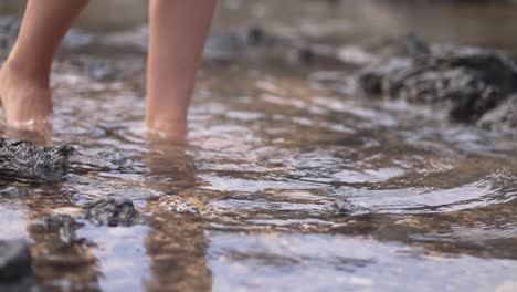 girl walking over black volcanic beach with small waves in fuerteventura, canary islands