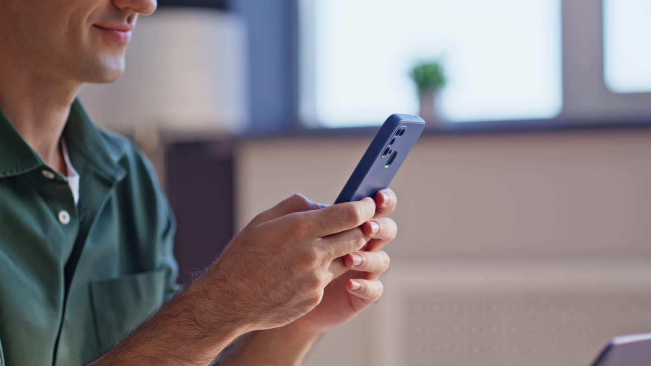 Smiling manager typing sms cellphone at remote workplace closeup. Positive man