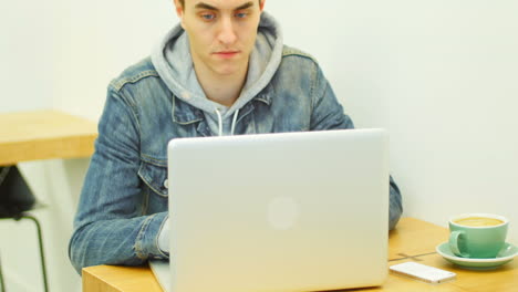 hombre usando una computadora portátil mientras toma café