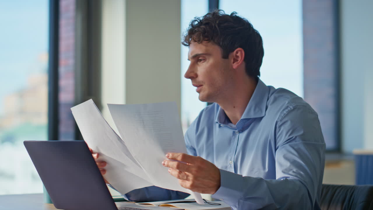 Overloaded manager reading documents sitting apartment table with laptop