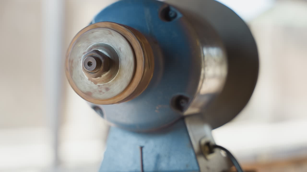Close up blue grinder spindle rust, workshop scene with soft natural light, shallow depth of field, worn metal collar and thread, carpenter preparing tool for sharpening, warm vintage tones
