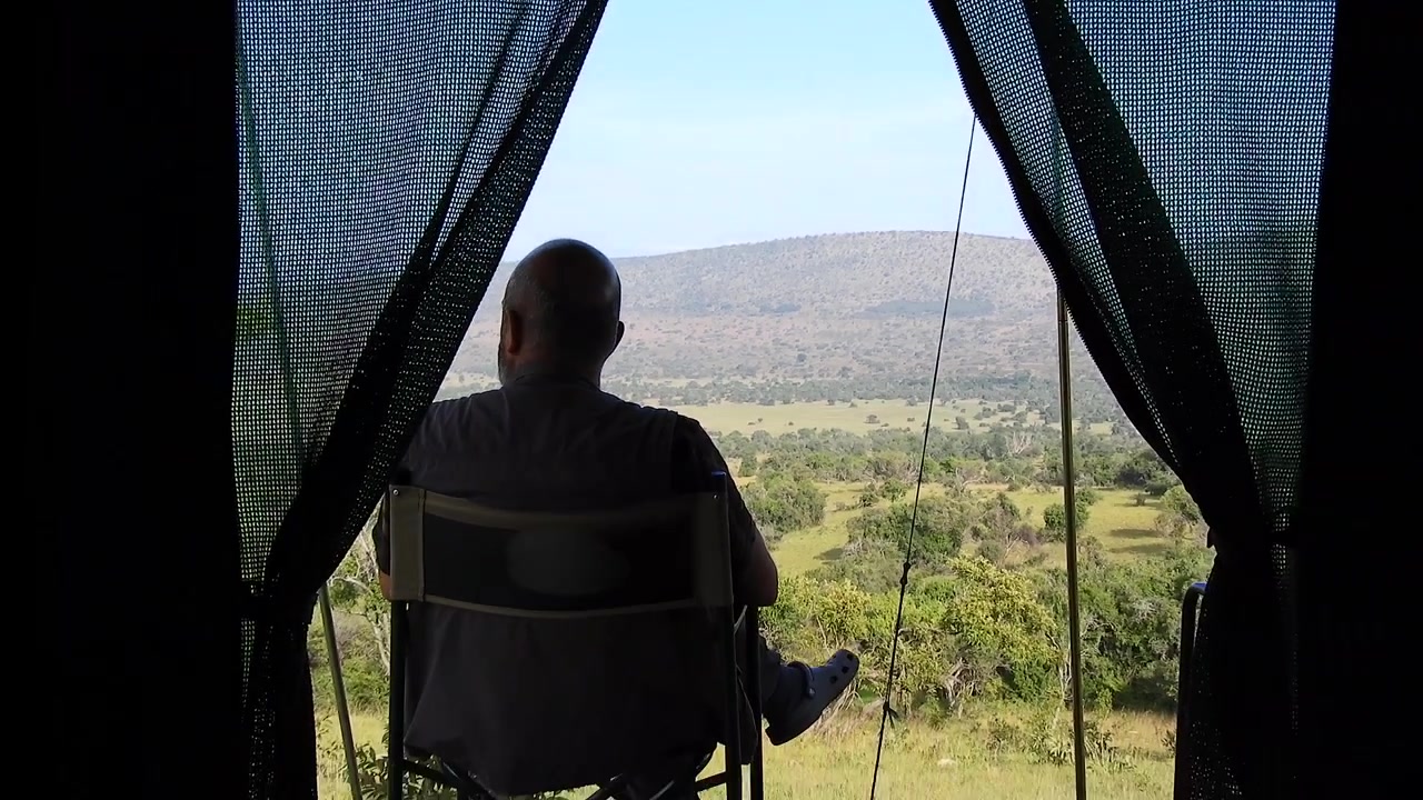 Man Sitting in Safari Tent Overlooking African Savanna