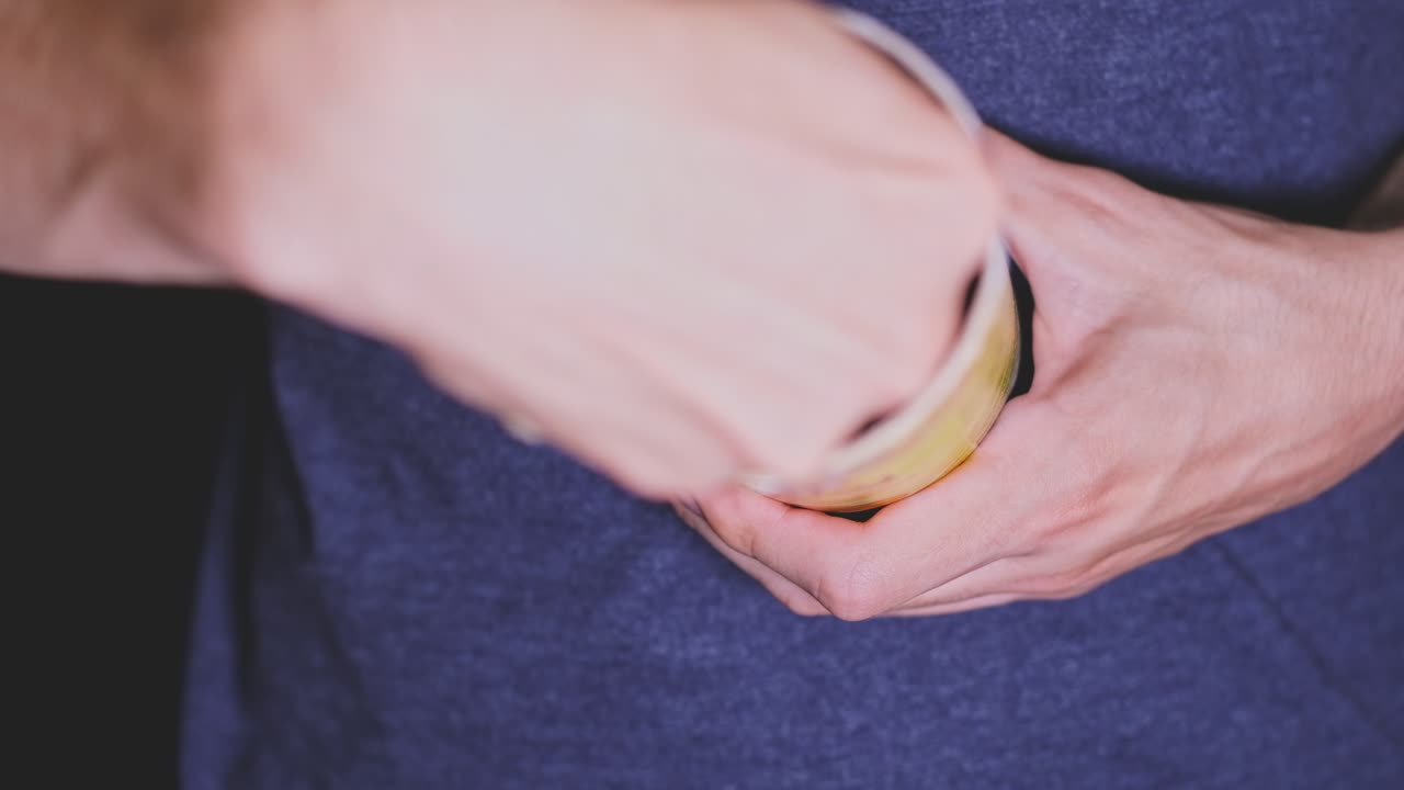Man's hands tries to take a chip from the cylindric bowl. Close up. Daily life problems