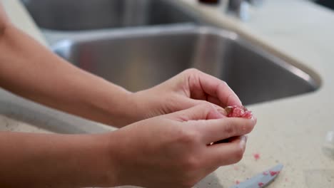 hands delicately extract caviar from finger lime in a well-lit kitchen environment, showcasing culinary preparation