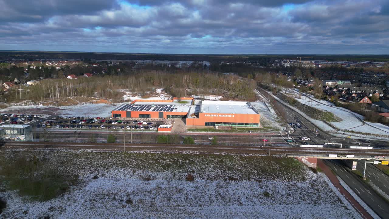 Indoor swimming pool with solar panels surrounded by snow and suburban homes in Falkensee Germany. Dramatic aerial view flight static tripod hovering drone