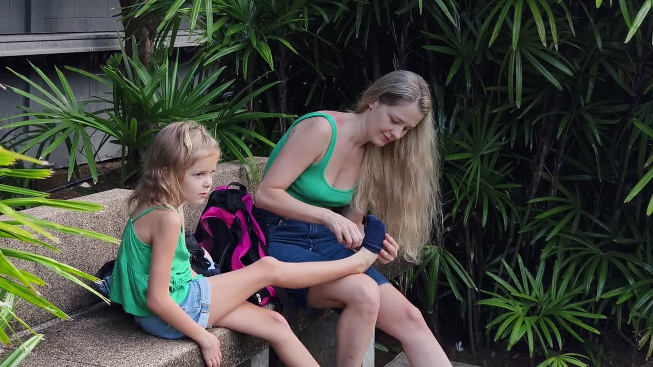 어머니 는 딸 이 공원 에서 양말 을 입는 데 도움 을 주고 있다