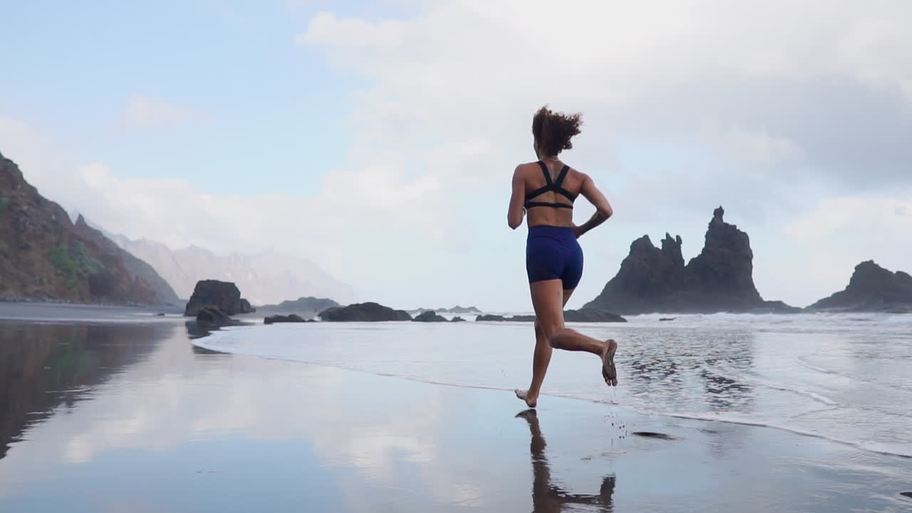 Sculpted Perfection: Slow Motion Morning Run of an Athletic Woman Along the Ocean's Edge