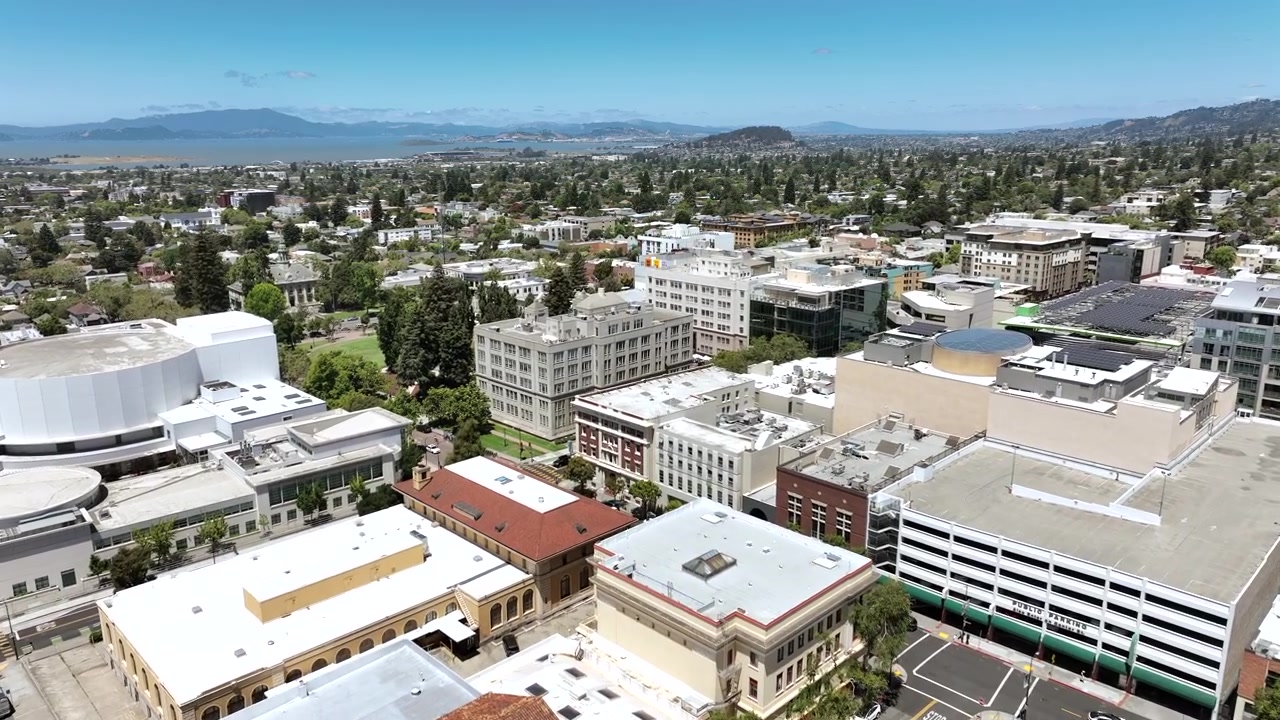 Filmato aereo ad alta quota con drone di downtown Berkeley, California, che mostra edifici commerciali, strade cittadine, quartieri circostanti e le dolci colline di East Bay sullo sfondo