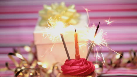 sparklers on a birthday cupcake with gift