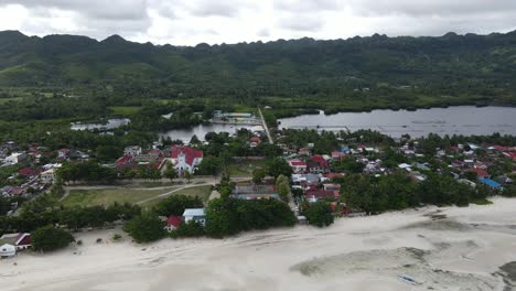 aerial drone fly above coastal village town and landscape in anda phillipines, cloudy skyline