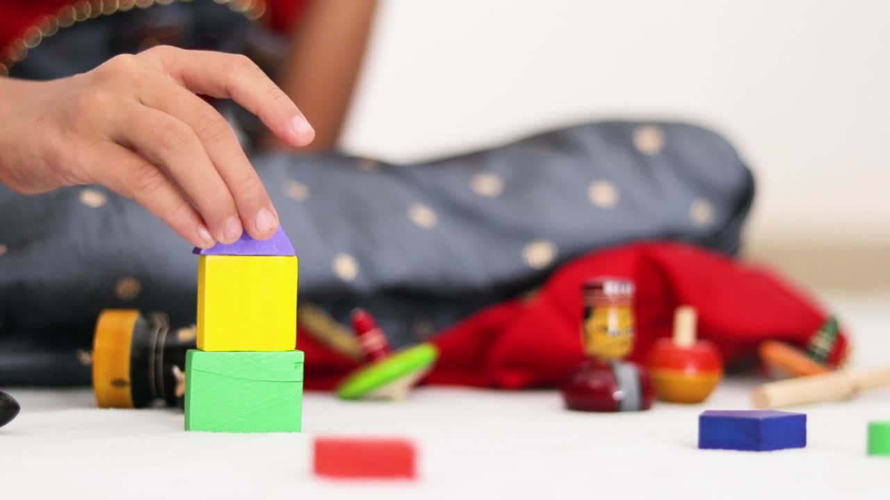 primer plano de manos de niños jugando con coloridos bloques de madera en casa en india