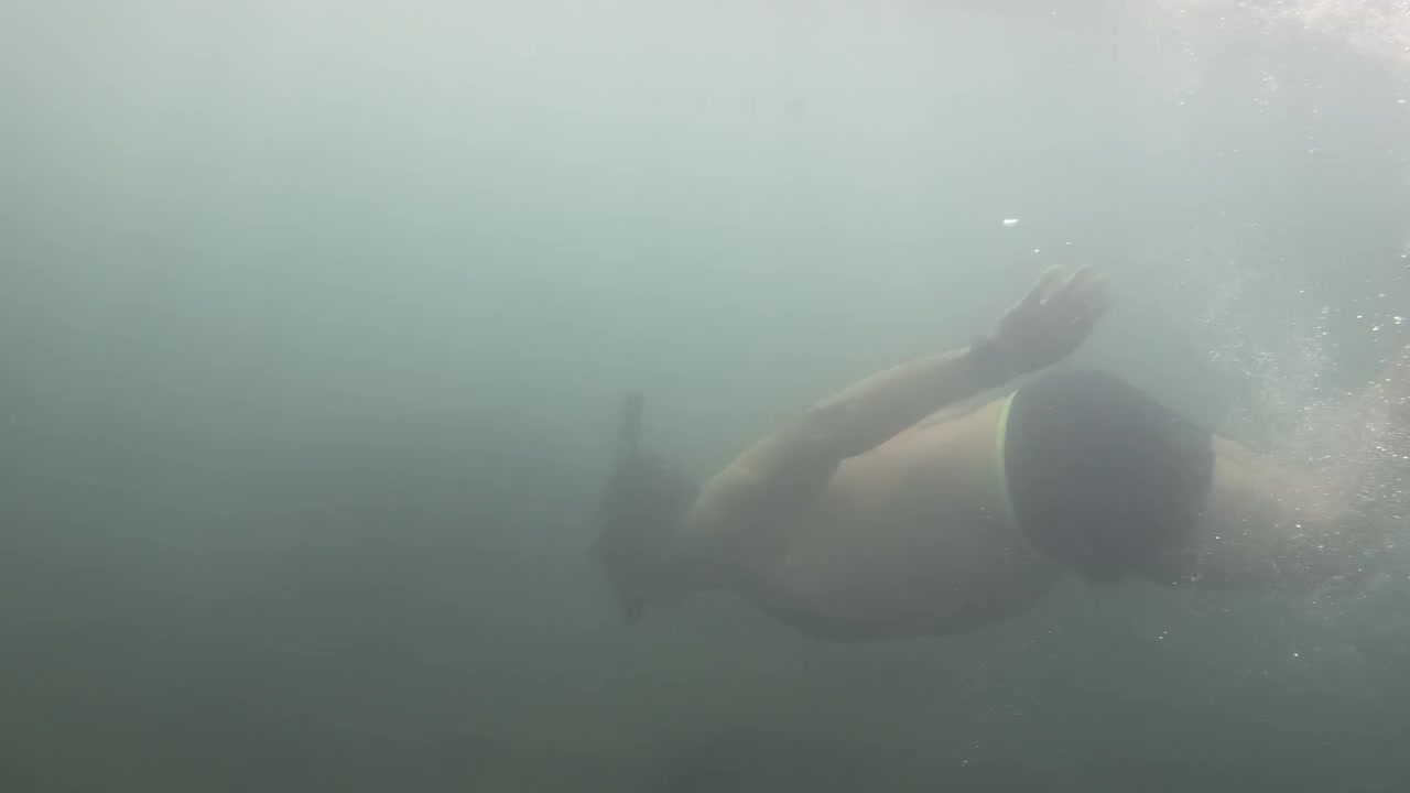 Man swimming underwater in ocean wearing snorkel gear, exploring the unknown depths and experiencing adventure in the sea