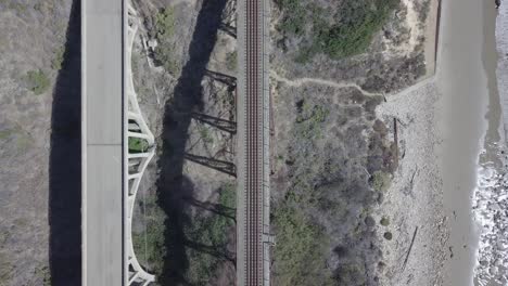 toma aérea de drones de ferrocarril y puente junto al océano con olas rompientes