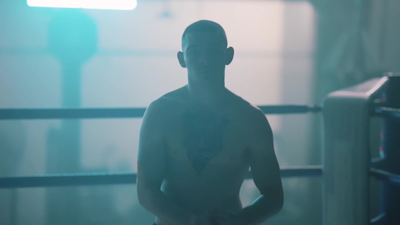 Shirtless Boxer with Tattoo Standing in a Moody Boxing Ring