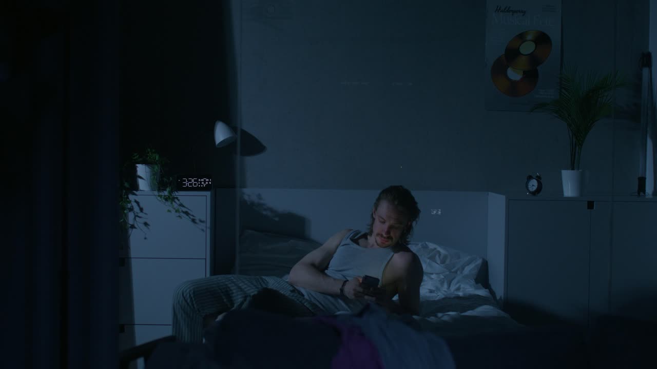 밤에 침대에 드폰을 사용하는 남자