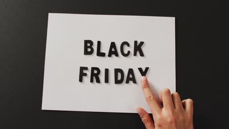 hand moving black friday text in black letters on white rectangle with black background