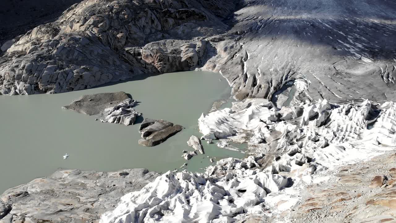 빙하 끝의 얼음 크레바스를 향해 스위스의 발레와 우리의 경계에 있는 푸르카 산길 근처의 론 빙하의 빙하 호수 위로 공중 비행