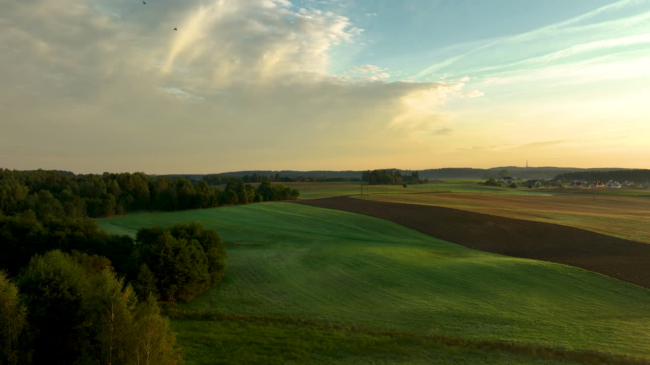 Countryside aerial view with farmland, forests, rolling fields and evening sky
