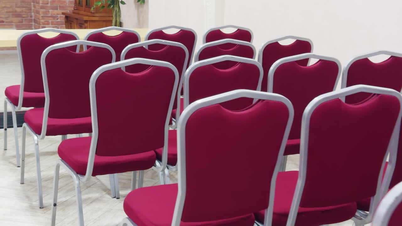 Pink chairs four in a row are placed indoors. Seat prepared for ceremony.