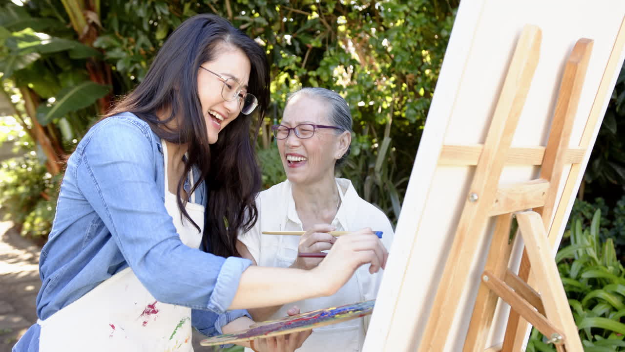 Teaching painting, Asian grandmother and granddaughter creating art together outdoors
