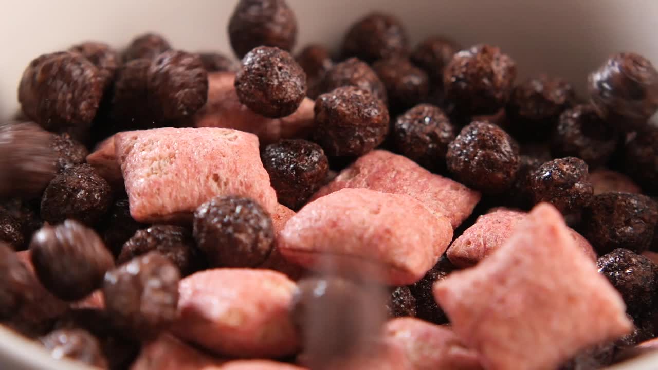 Cereal de chocolate caindo em uma tigela com cereal rosa