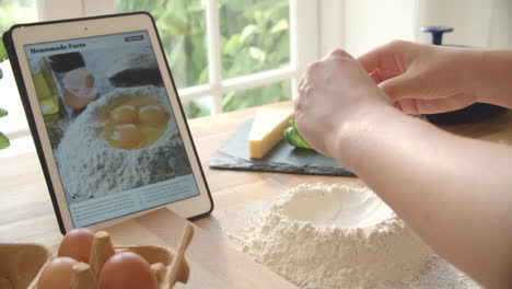 persona que sigue la receta de pasta utilizando una aplicación en una tableta digital