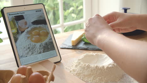 person following pasta recipe using app on digital tablet