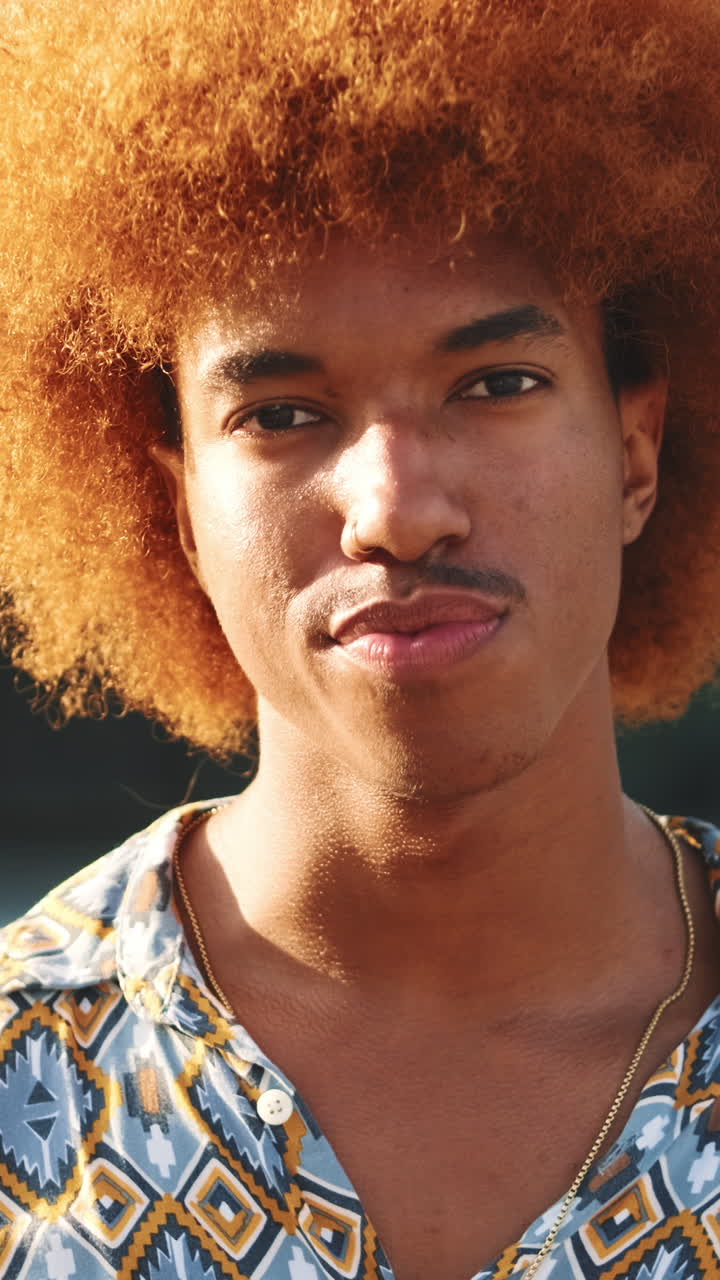 Ritratto ravvicinato di un giovane uomo con capelli afro che guarda in camera