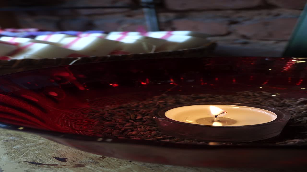 una vela encendida en un cuenco rojo en una mesa de madera