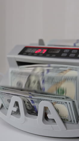 little money counting machine turning money. laptop with a black screen and a curve at backdrop in blur. vertical video