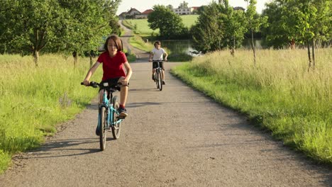 cute happy children, brothers, riding bikes in the park on a sunny summer day, talking and laughing