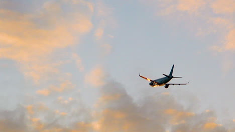 airplane flying in cloudy sky during sunset