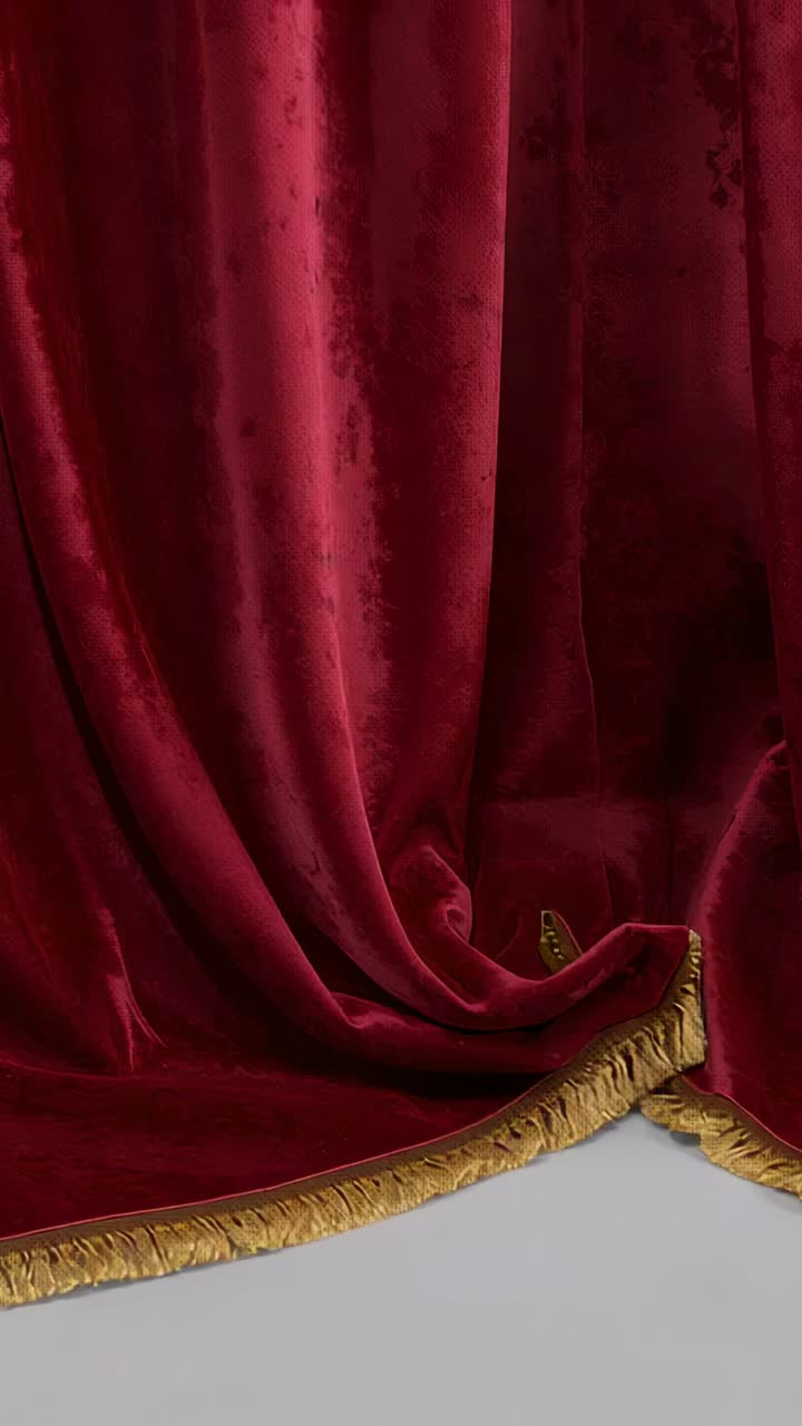 Vertical video: Shifting red velvet curtain from light shift on pale studio floor, with gold fringe