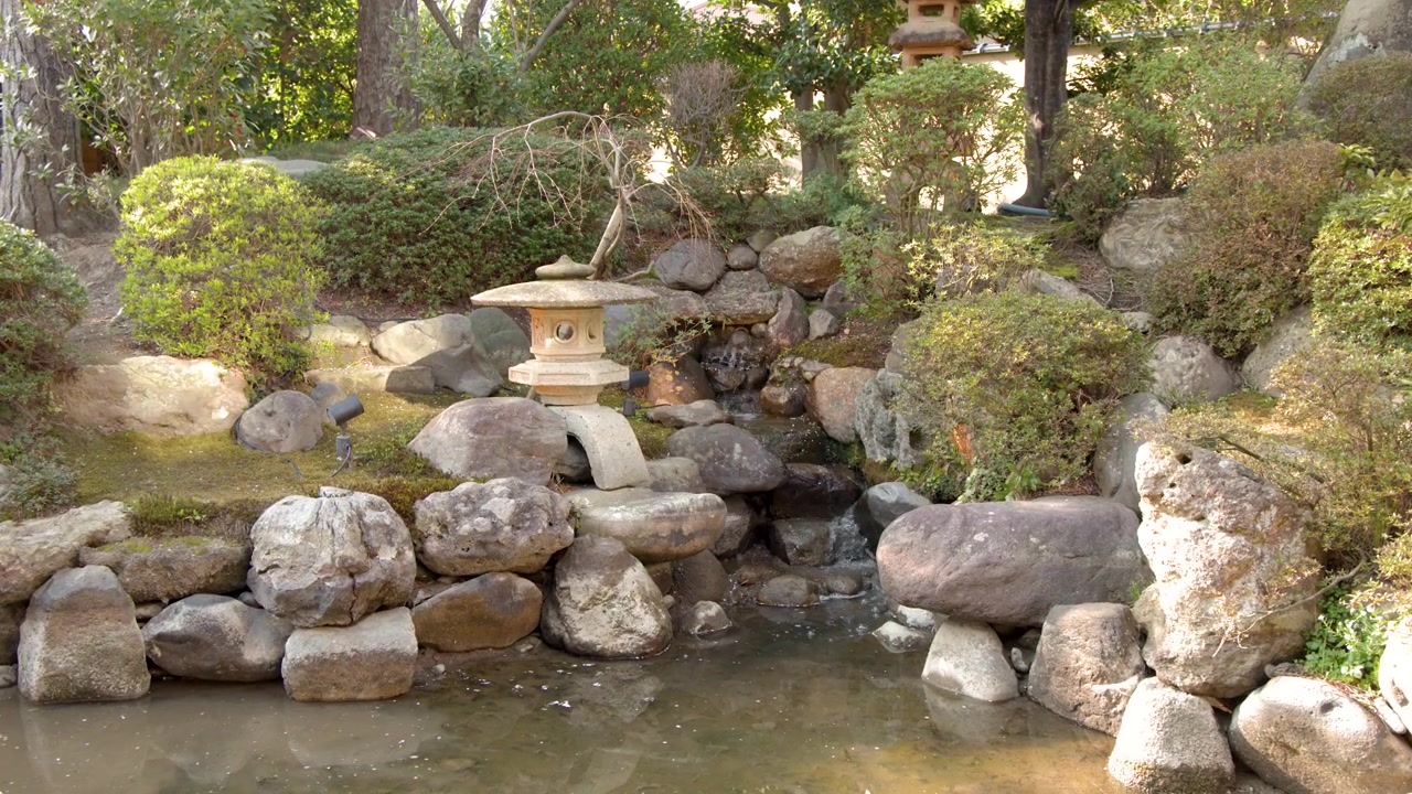 Lanterna di pietra tradizionale giapponese in uno stagno da giardino tranquillo