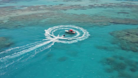 aerial view of a boat creating a circular wake in clear turquoise tropical waters