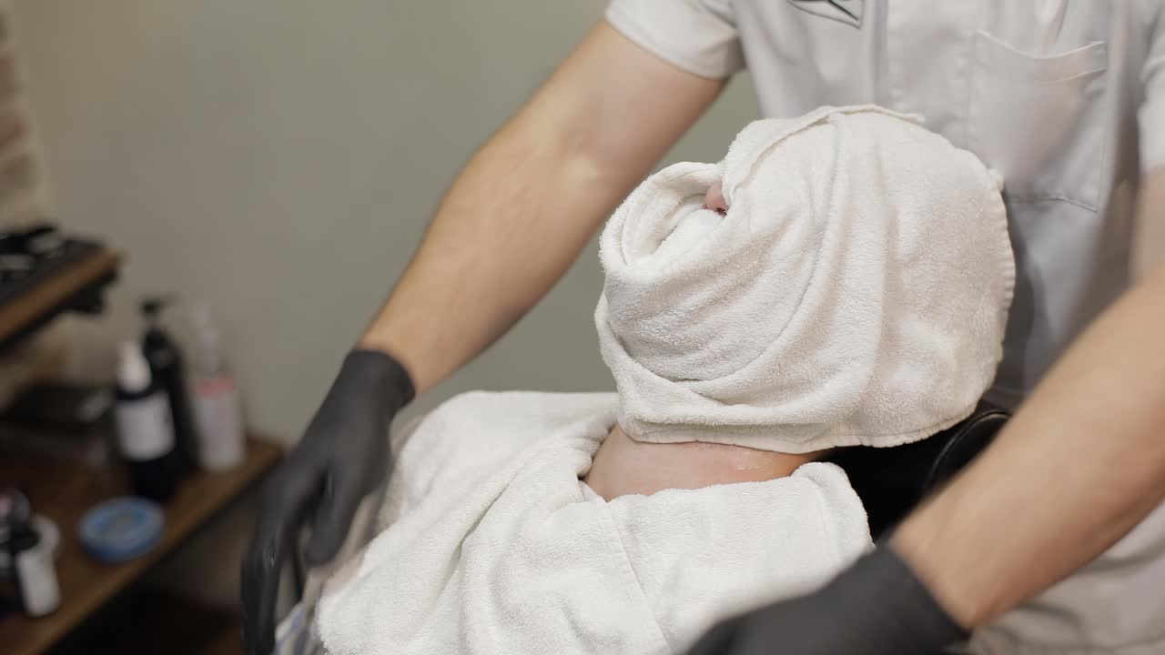 cliente con barba negra durante el afeitamiento de la barba en la barbería. novio, masculino