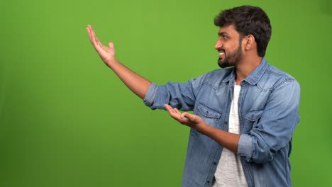 retrato de un joven asiático dando la bienvenida con las manos abiertas en una sesión de fotos con fondo verde