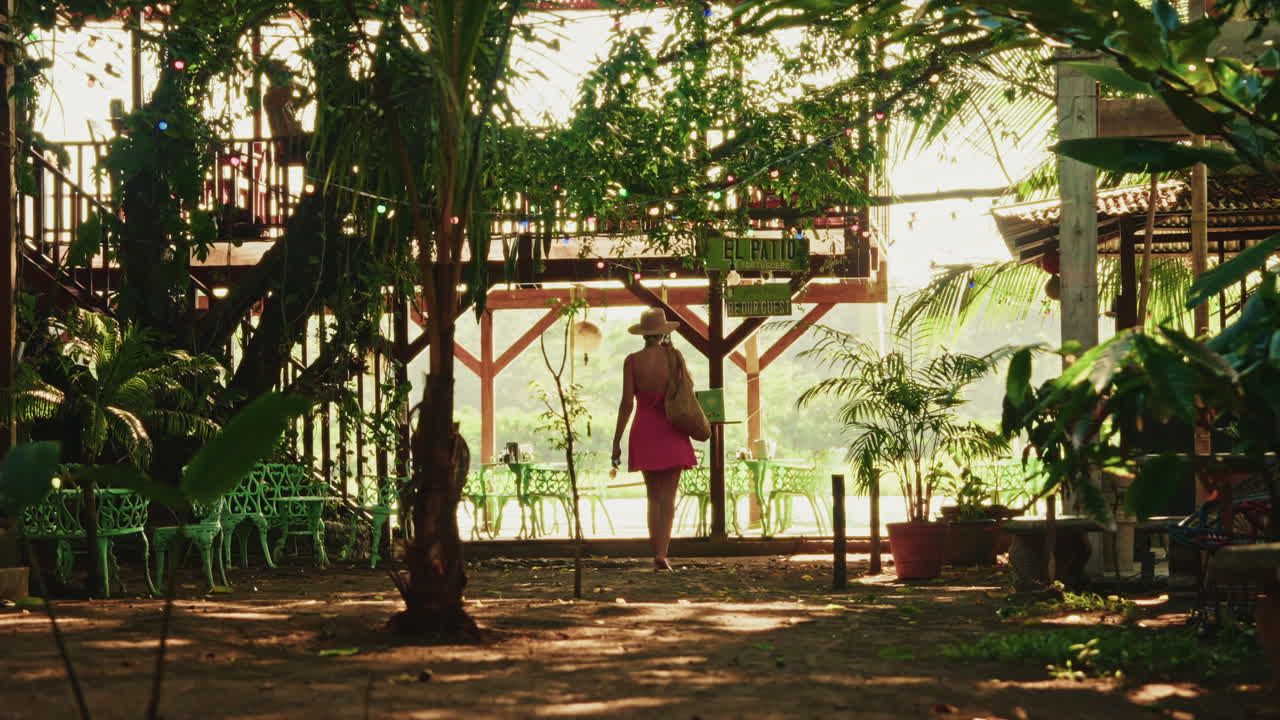 Back shot of a young lady with a pink dress and a hat exploring Tortuguero National Park in Costa Rica.
