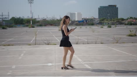woman walking in a parking lot using a phone