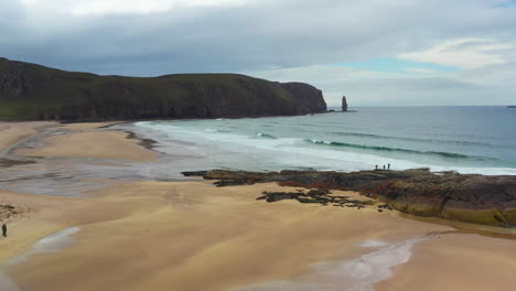 Revealing-cinematic-drone-shot-of-rocky-outcroppings-on-Sanwood-Bay-Beach-in-Sutherland-Scotland-and-north-atlantic-ocean-waves